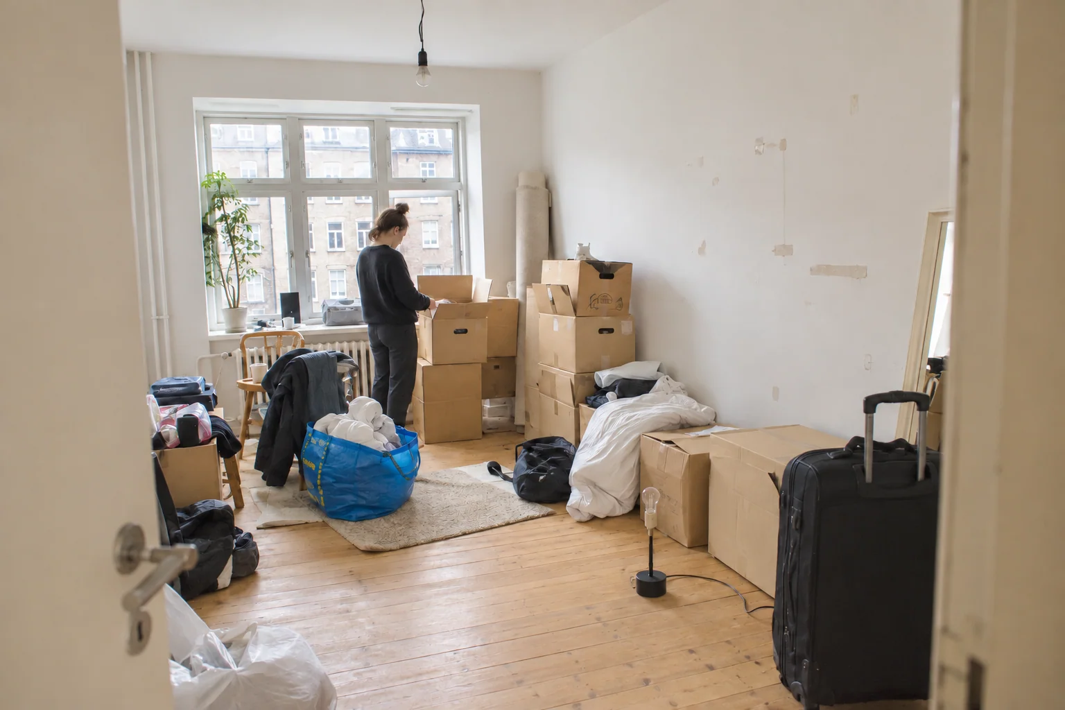 Moving boxes, a rolled-up rug and a suitcase in an apartment