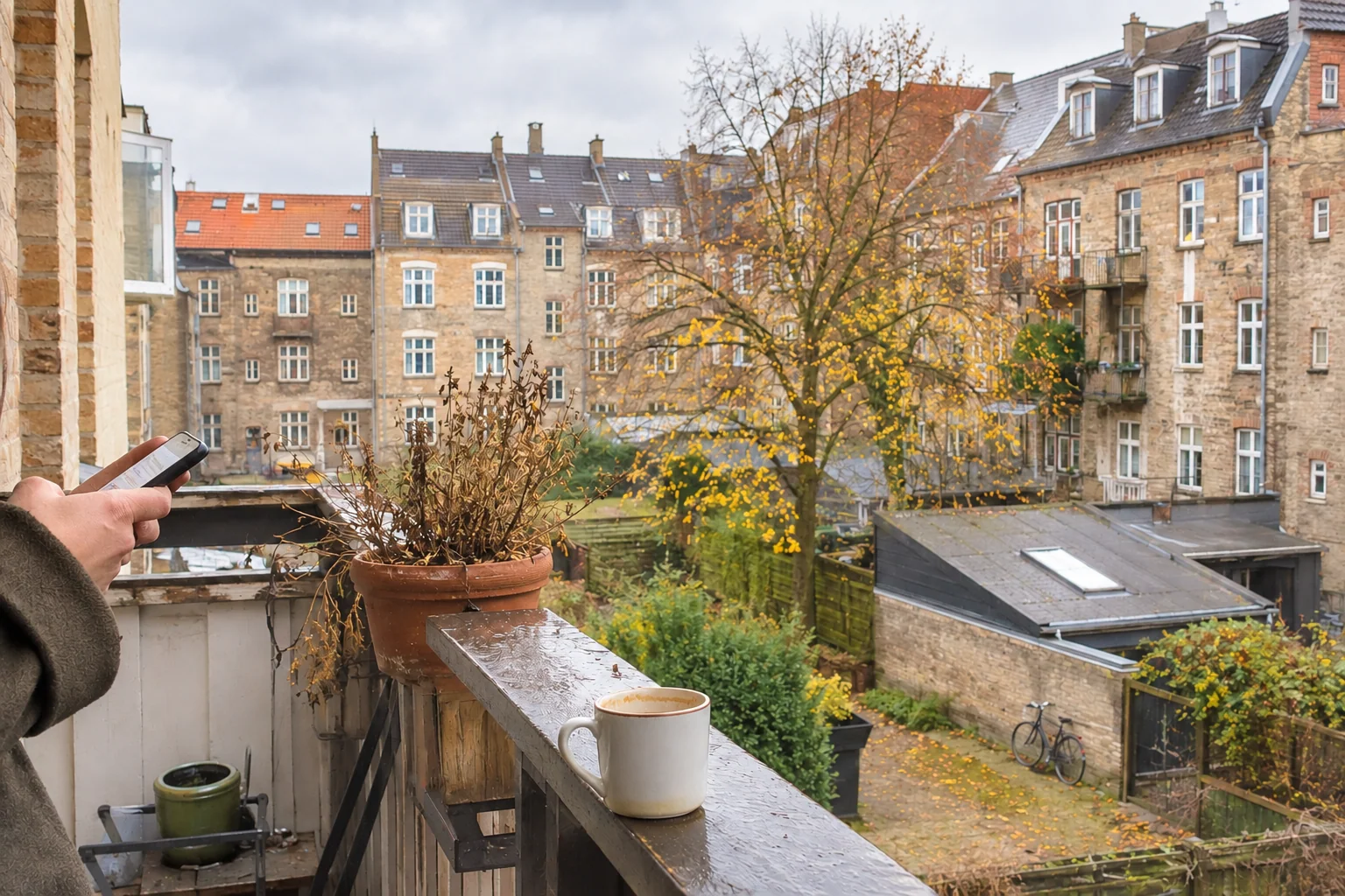 A phone and a coffee cup on a wet Copenhagen balcony