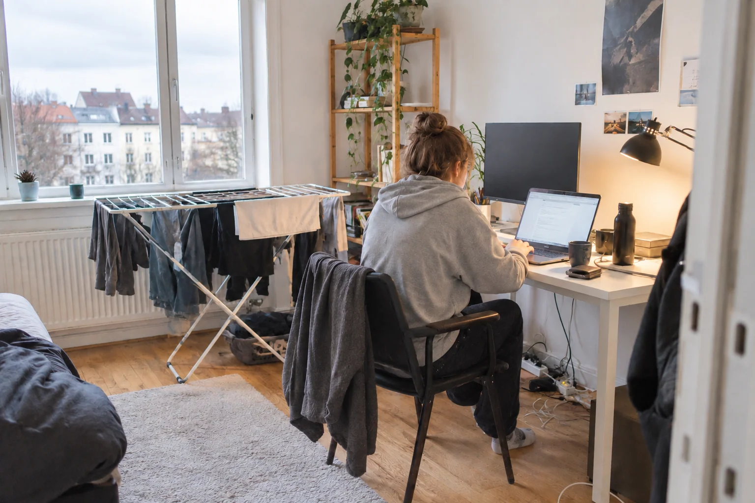 A person working at a small desk with laundry in the background